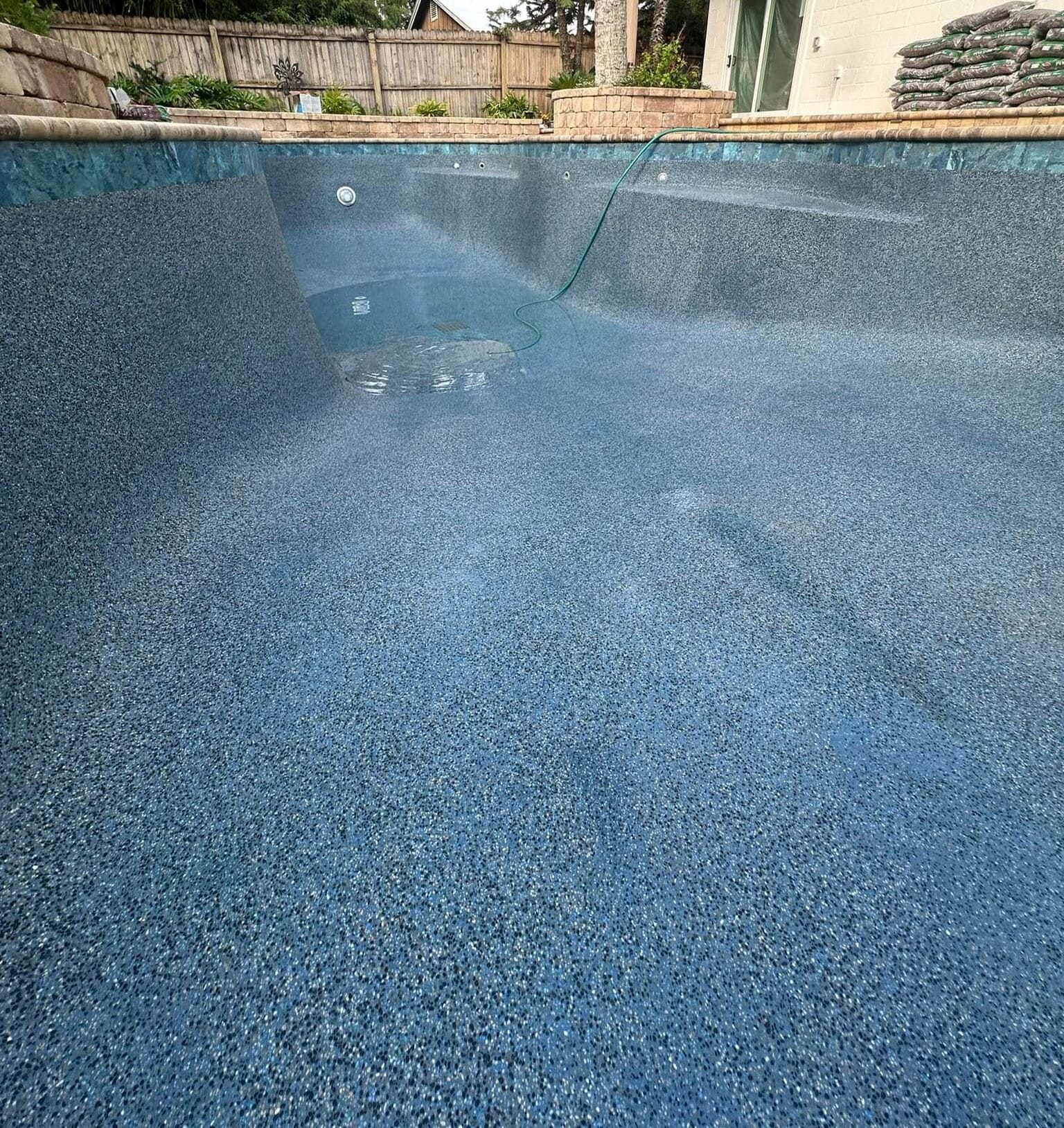 pool rejuvenation cleaning Jacksonville FL - A sparkling clean swimming pool surrounded by lush greenery, showcasing pool rej