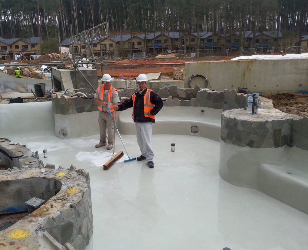 A worker named Robert applying plaster to a pool surface, showcasing pool plastering challenges in England.