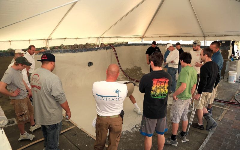 A trainer demonstrating pool plaster techniques during a workshop, emphasizing pool plaster training Jacksonville FL.